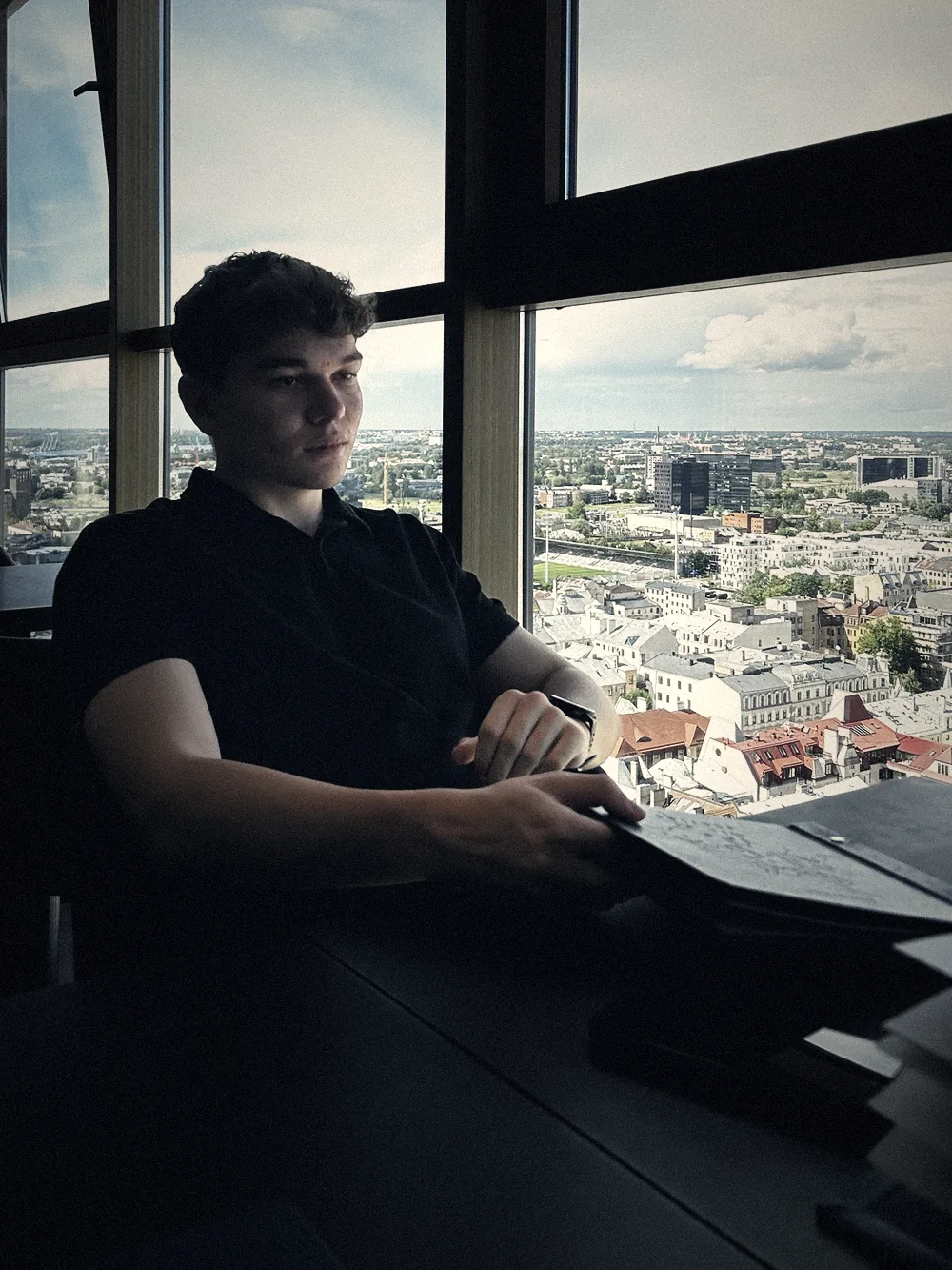 Marcel am Fenster über den Dächern einer Stadt